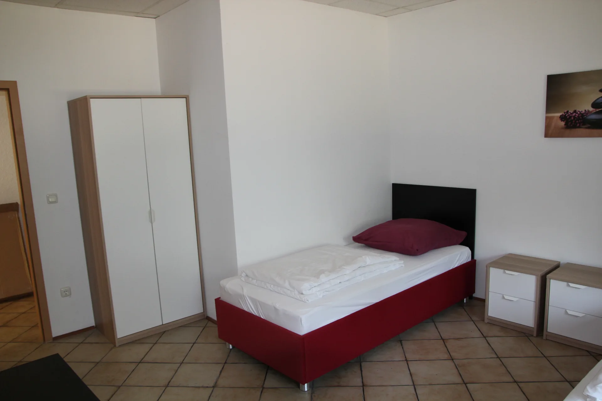Einzelzimmer mit Bett, Schrank und Nachttisch